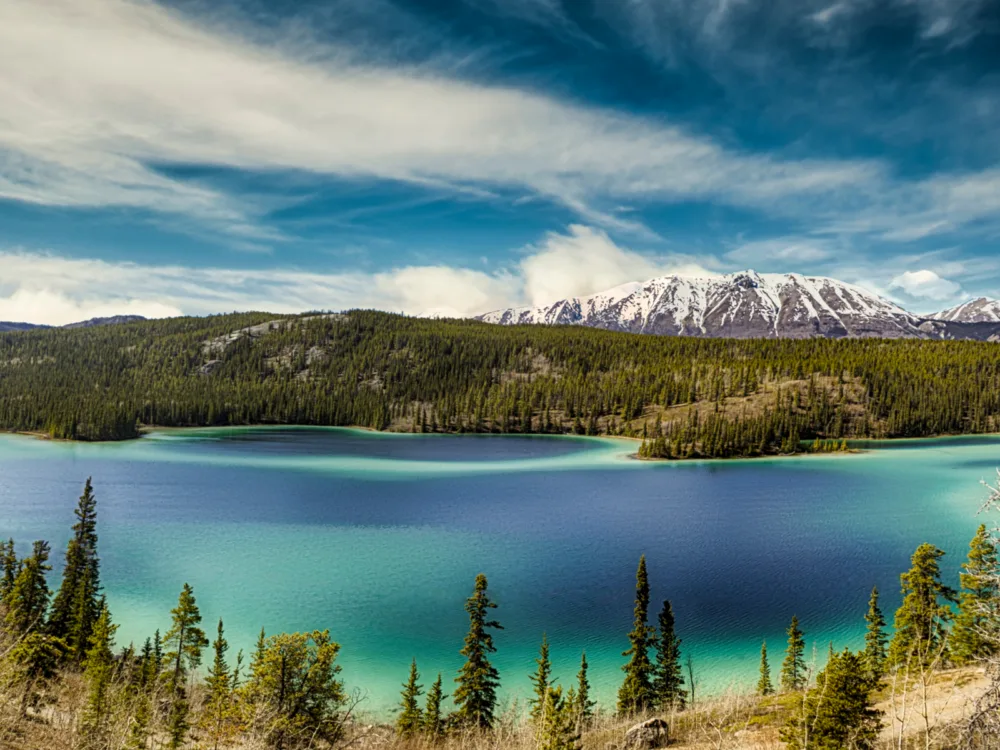 Aerial view of the calm and clear waters of Emerald Lake and an icy peak mountain at the Yukon Territory, one of the best places to visit in Canada