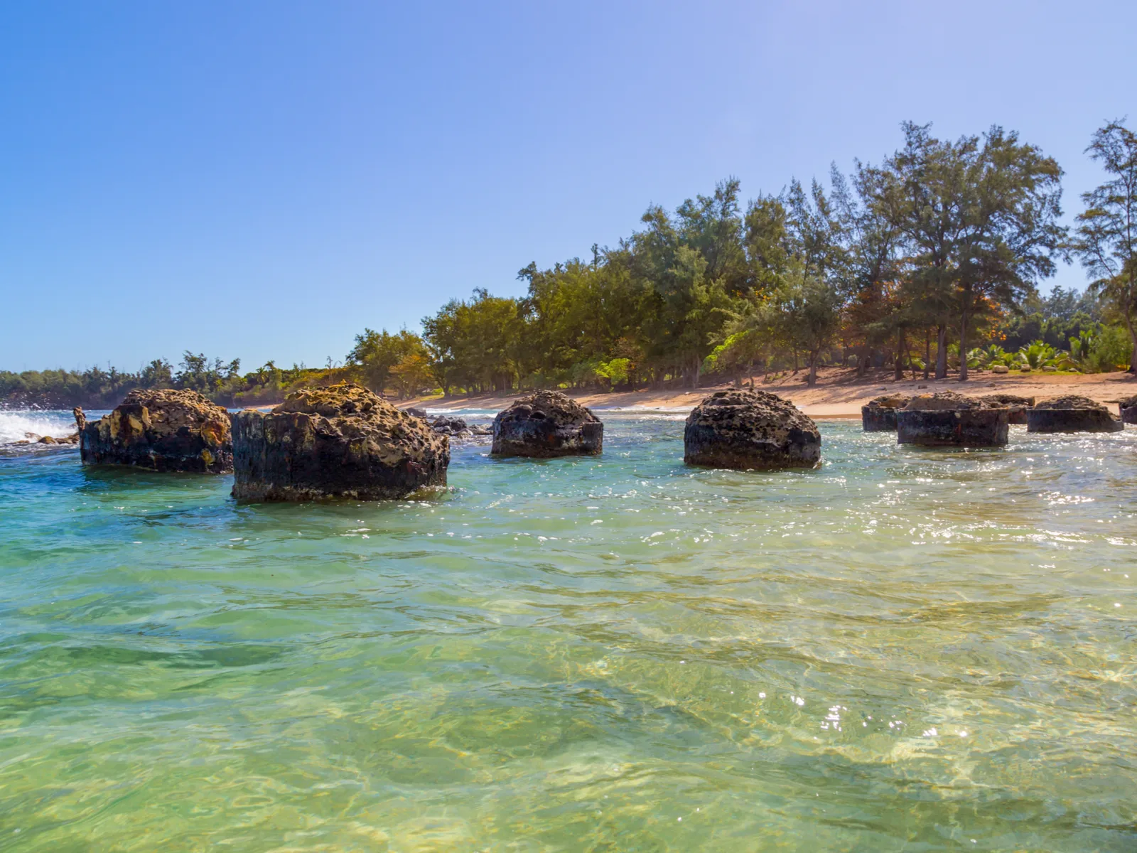 Condemned old pier columns at Anahola Beach, one of the best beaches in Kauai, with sparkling clear water