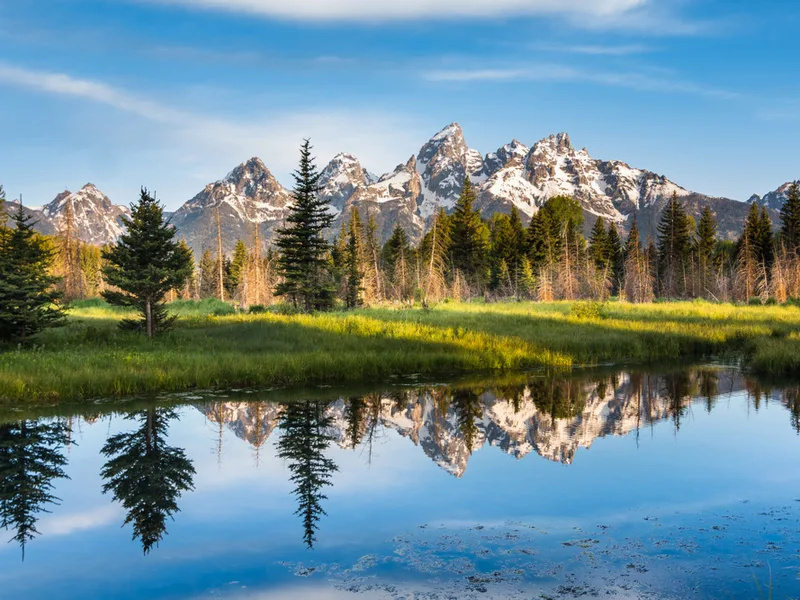 Gorgeous view of the Grand Tetons overlooking a lake for a piece on the best National Parks in the US