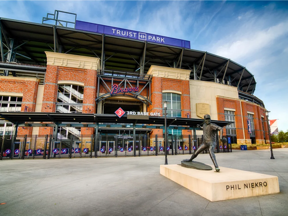 Statue of Phil Niekro in a pitching pose in front of the empty 3rd Base Gate entrance at Truist Park, one of the best tourist attractions in Georgia, with the large signage of Braves overhead