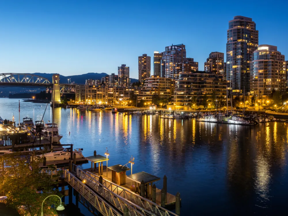 Illuminated Vancouver City skyline and a bridge at dusk reflected on calm waters, one of the best places to visit in Canada