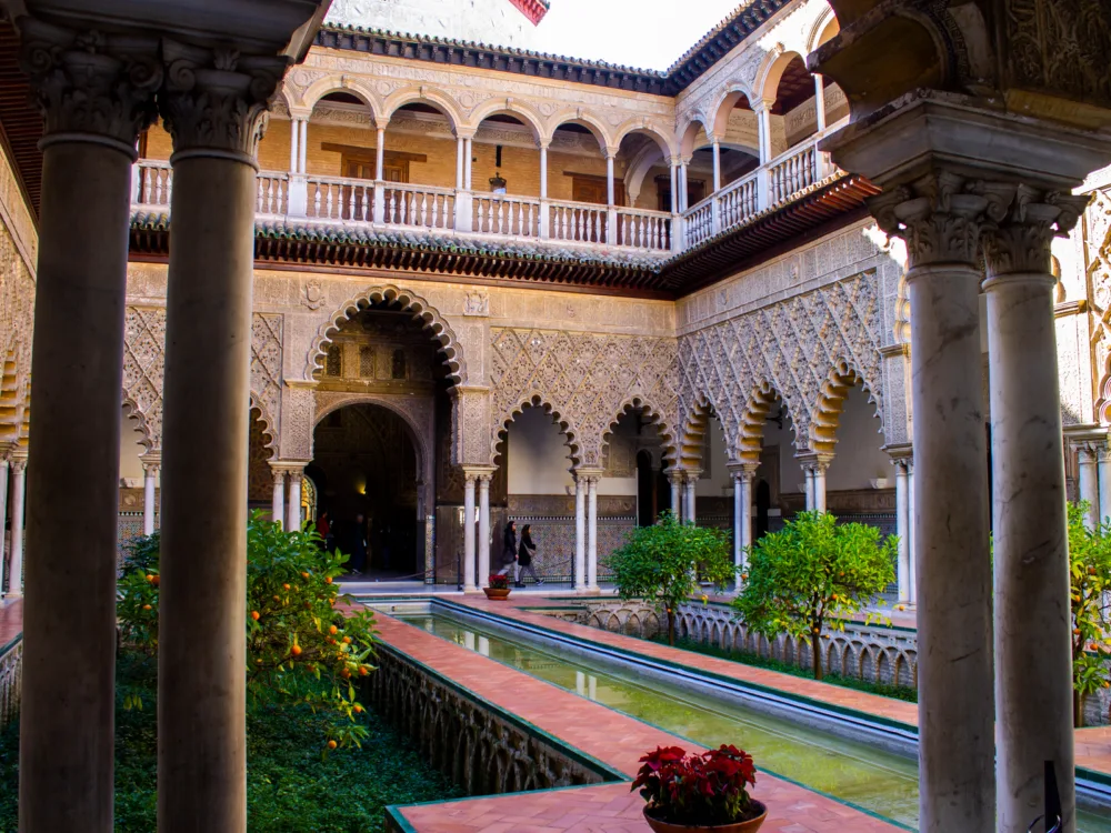 Emerald water on the small center pool at the courtyard and heavily decorated walls at Royal Alcázar of Seville in Spain, a Game of Thrones filming locations you can visit