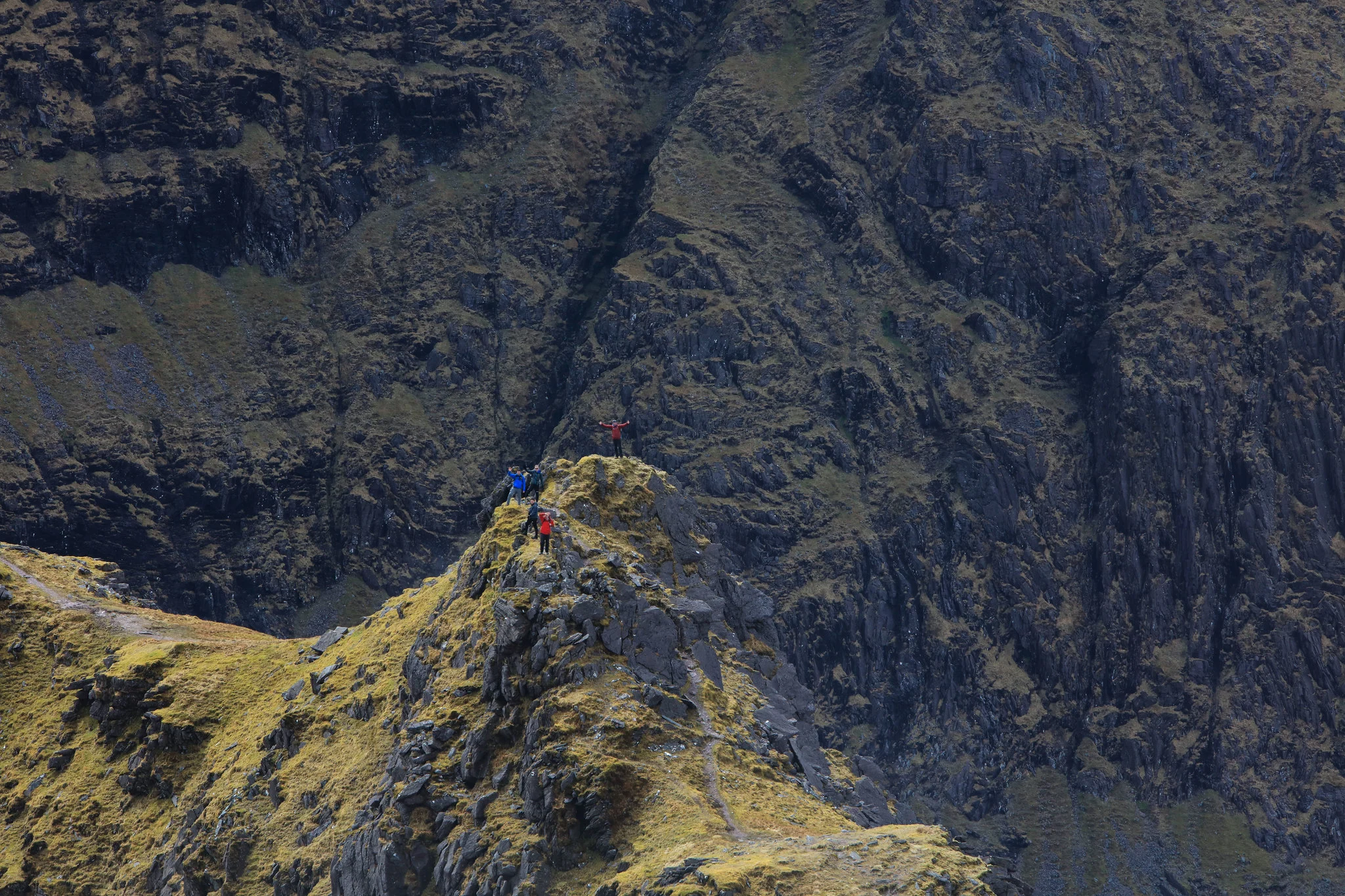 Five hikers posing on the tall rocky peak of Coomloughra Horseshoe Loop Walk at MacGillycuddy’s Reeks, named as one of the best hikes in Ireland