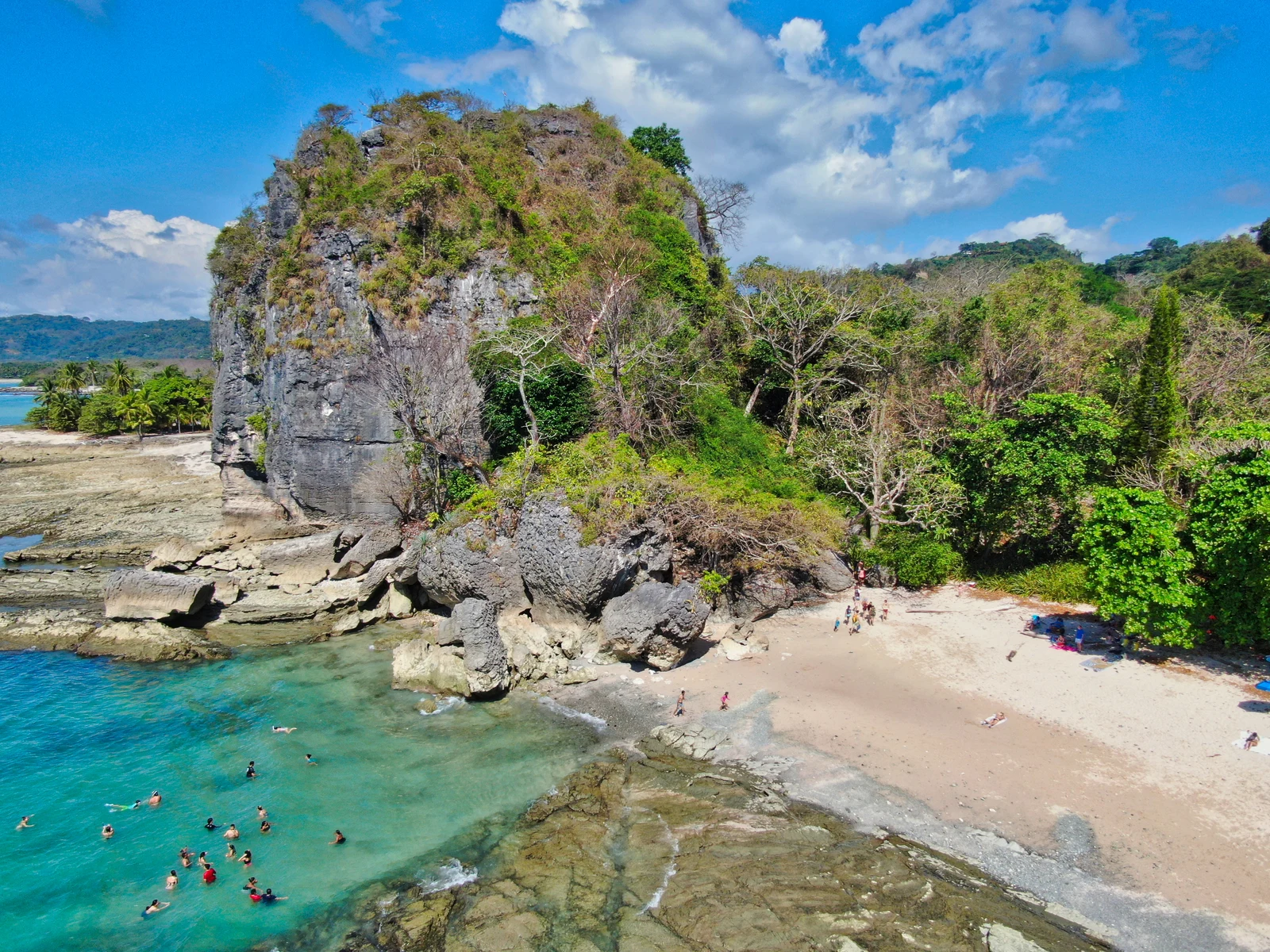 Aerial view of a huge boulder and people swimming on the clear waters of Santa Teresa and Malpais Beach, a piece on the best beaches in Costa Rica