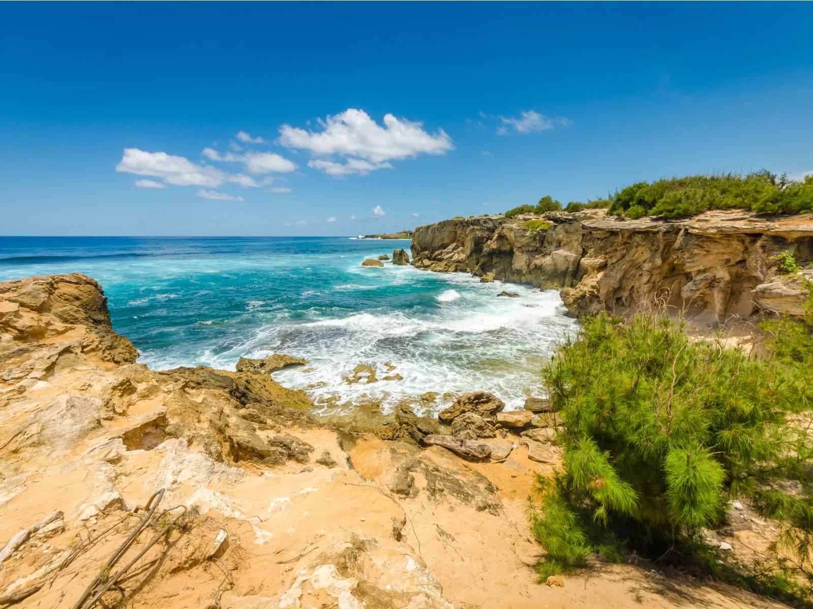 Foamy waves at the cliffs along the coast of Mahaulepu Beach, considered one of the best beaches in Kauai