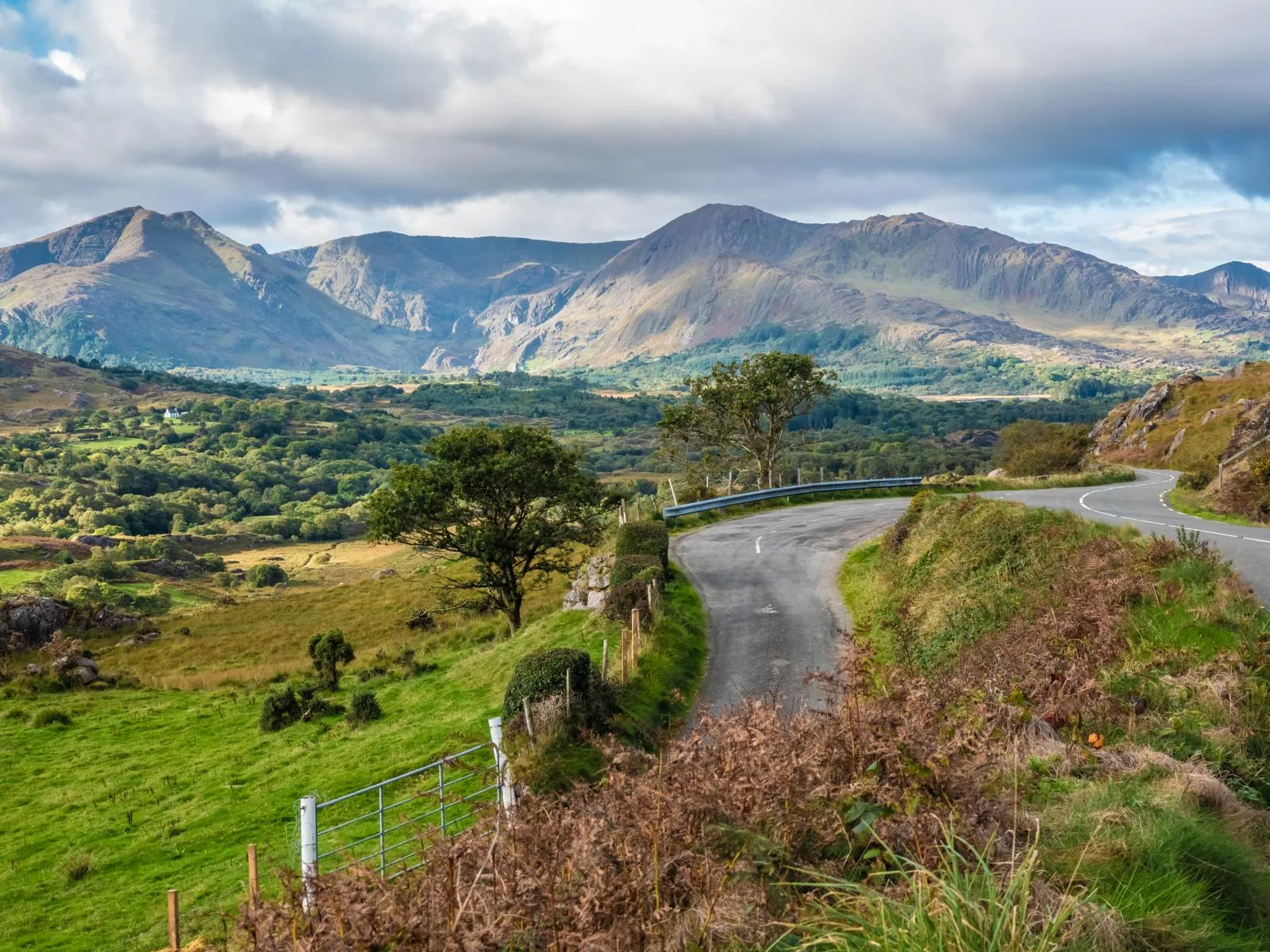 Merging winding roads surrounded by green landscape leading to tall mountains at Beara Way, a piece on the best hikes in Ireland