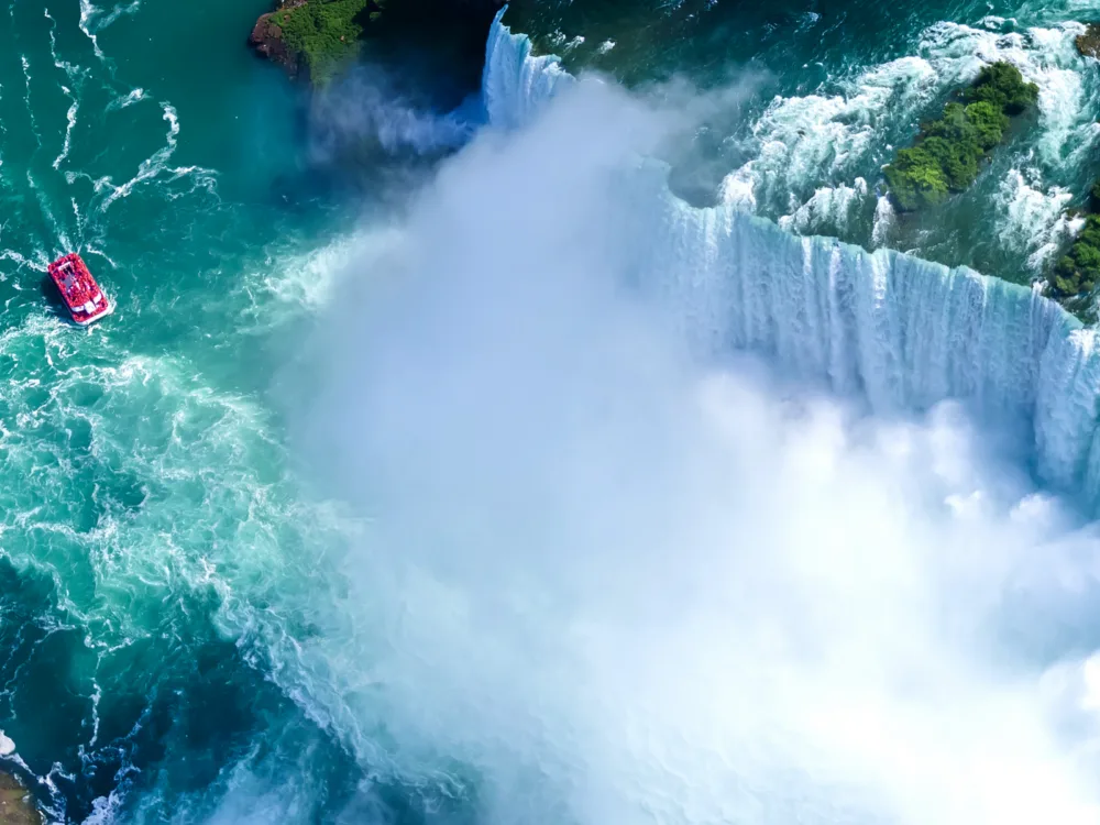 Aerial view of a red boat going towards the breathtaking Niagara Falls, Ontario, one of the best places to visit in Canada