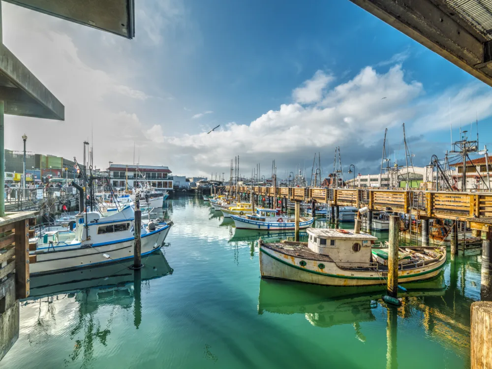 Empty fishing boats docked on the emerald water at Fisherman's Wharf, a piece on the best places to visit in San Francisco